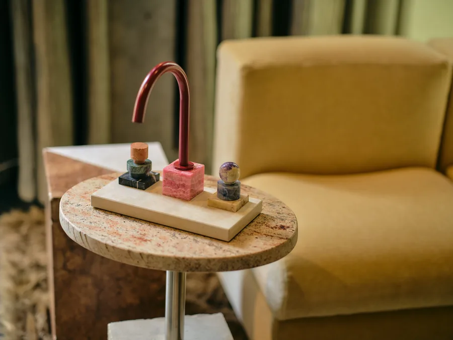 The Fabian Freytag tap for Dornbracht Atelier on a stone side table beside a yellow armchair