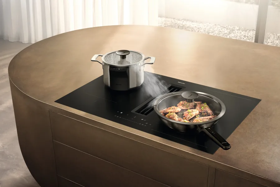 Miele KMDA 8683 FL induction hob with integrated extractor in a bronze kitchen island, steam drawn into the central vent